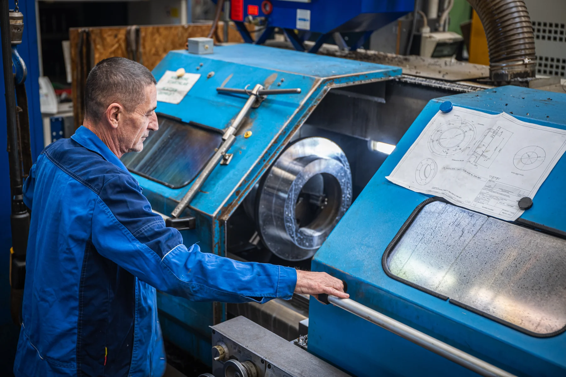 Dreher an der CNC-Maschine mit technischer Zeichnung